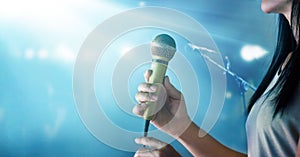 Woman holding microphone and singing on concert stage background