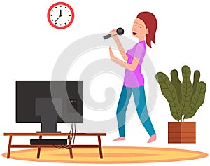 Woman holding microphone and singing music in karaoke. Girl stands with mike next to TV at home