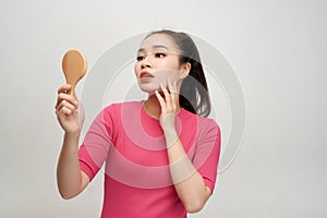 Woman holding a mirror, touch and worrying about her face