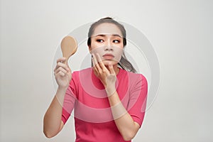 Woman holding a mirror, touch and worrying about her face