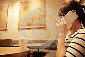 Woman holding mobile phone and call sitting alone in restaurant