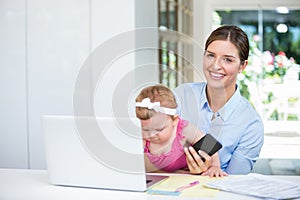 Woman holding mobile phone while sitting with baby girl