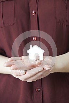 Woman Holding Model House In Palm Of Hand