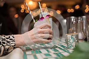 Woman holding mojito cocktail in hand from bar counter in nightclub