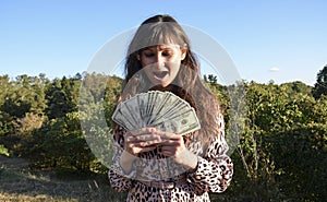 Woman holding money with delight. She is shocked how she easily win dollars online