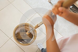 Woman holding a mop spinning in the bucket to cleaning and mopping the floor in the living room. Woman doing chores at home.