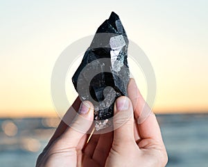 Woman holding Morion Smokey Quartz with Chlorite in her hand at sunrise