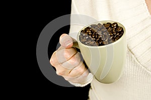 Woman holding mug of coffee beans