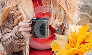 Woman holding mug of coffee in the hands outdoor. Beautiful woman drinking coffee in autumn park