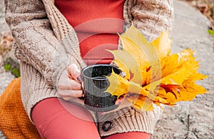 Woman holding mug of coffee in the hands outdoor. Beautiful woman drinking coffee in autumn park