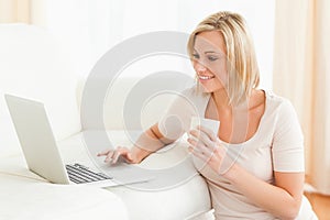 Woman holding a mug while using a laptop