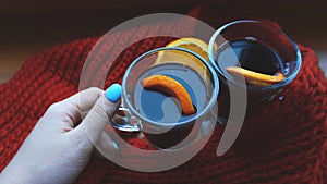 Woman holding mulled wine with spices and citrus fruit in her hand, close up