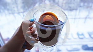 Woman holding mulled wine with spices and citrus fruit in her hand, close up