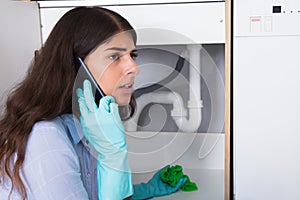 Woman Holding Napkin Under Sink Pipe Leakage Calling Plumber photo