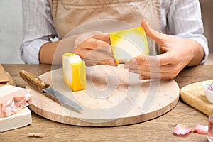 Woman holding natural handmade soap at table, closeup