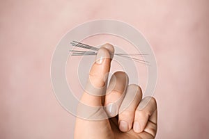 Woman holding needles for acupuncture on pink background, closeup