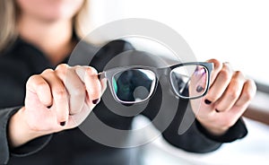 Woman holding new glasses. Lenses and spectacles getting fix and repair by professional optician.