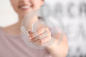 Woman holding occlusal splint on light background, closeup