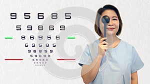 Woman holding ocluder with eye vision examination chart