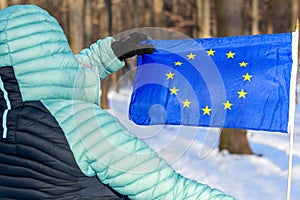 Woman holding an open European Union flag, Winter scenery, Concept, manifesting attachment to common European values