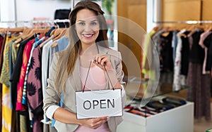 Woman holding open sign in clothes shop