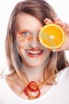 Woman holding orange on her eye