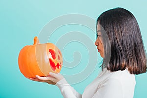Woman holding orange model pumpkins and looking it