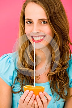 Woman holding orange with straw