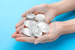 Woman holding packages with contact lenses and case on turquoise background, closeup