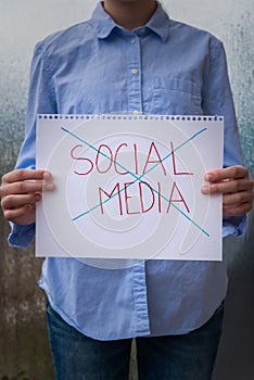 Woman holding page with the words social media crossed out