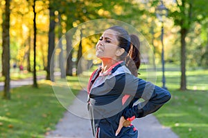 Woman holding painful back in park