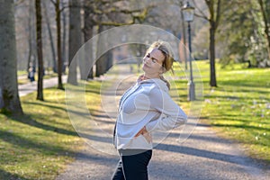 Woman holding painful back in park