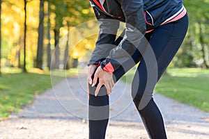 Woman holding painful knee in park