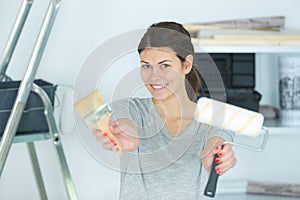 woman holding paint roller and brush