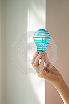 Woman holding painted light bulb near window