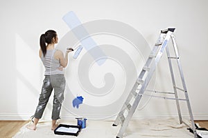 Woman Holding Paintroller While Analyzing Paint On Wall