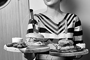 Woman holding pair of round wooden trays with burgers