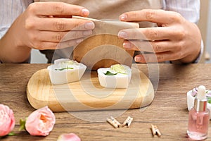 Woman holding paper bag with handmade soap at wooden table, closeup