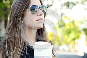 Woman holding paper coffee cup in the street.