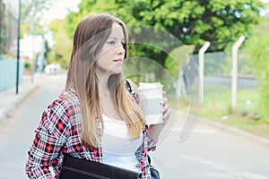 Woman holding paper coffee cup in the street.