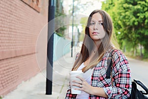 Woman holding paper coffee cup in the street.