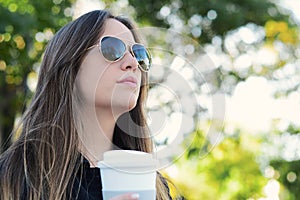 Woman holding paper coffee cup in the street.