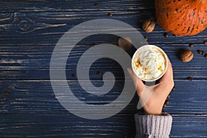 Woman holding paper cup with pumpkin spice latte