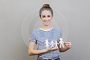 Woman holding paper family chain, looking at camera with toothy smile.