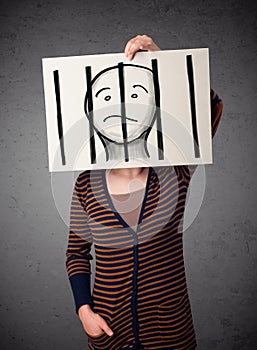 Woman holding a paper with a prisoner behind the bars on it in f