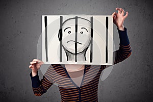 Woman holding a paper with a prisoner behind the bars on it in f