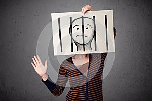 Woman holding a paper with a prisoner behind the bars on it in front of her head
