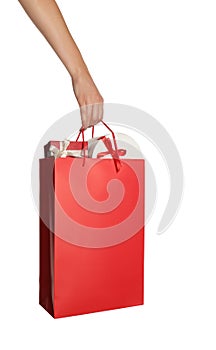 Woman holding paper shopping bag full of gift boxes on white background