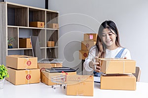 Woman holding parcel boxes to write customer address information before shipping to customers via private transport service.