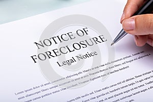 Woman Holding Pen Over Notice Of Foreclosure Document